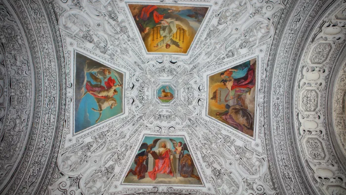 White stucco vault holds four frescoed panels of the evangelists arranged around a central medallion.