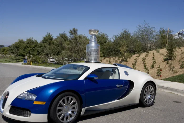 The Stanley Cup stands on the roof of a blue and white Bugatti Veyron.